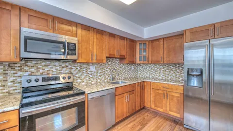 a kitchen with stainless steel appliances granite countertop a refrigerator and a stove top oven