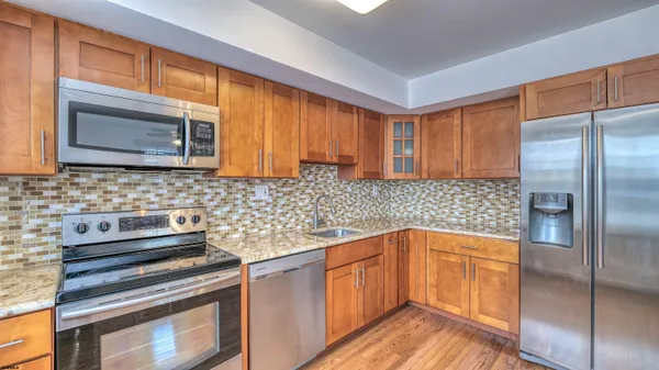 a kitchen with stainless steel appliances granite countertop a refrigerator and a stove top oven