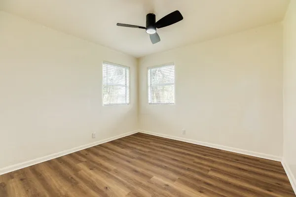 an empty room with wooden floor and ceiling fan