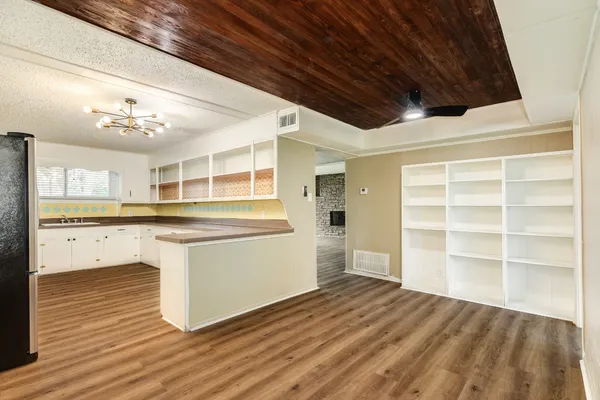 a room with a wooden floor and white cabinets