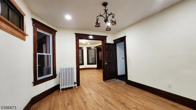 a view of a hallway with wooden floor and chandelier