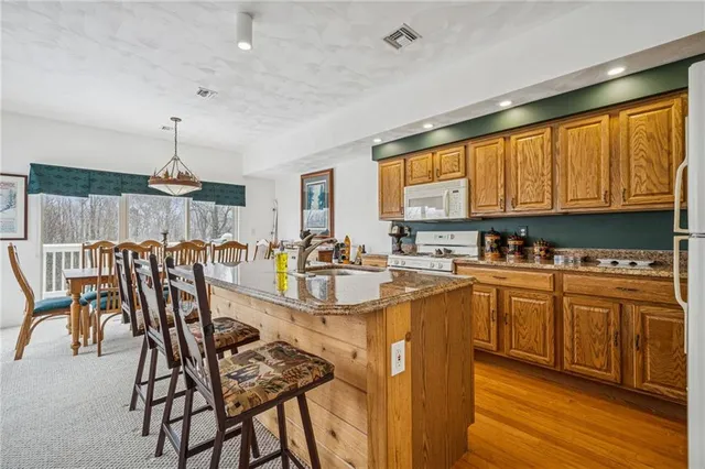 a kitchen with stainless steel appliances granite countertop a stove top oven a sink dishwasher and a dining table with wooden cabinet