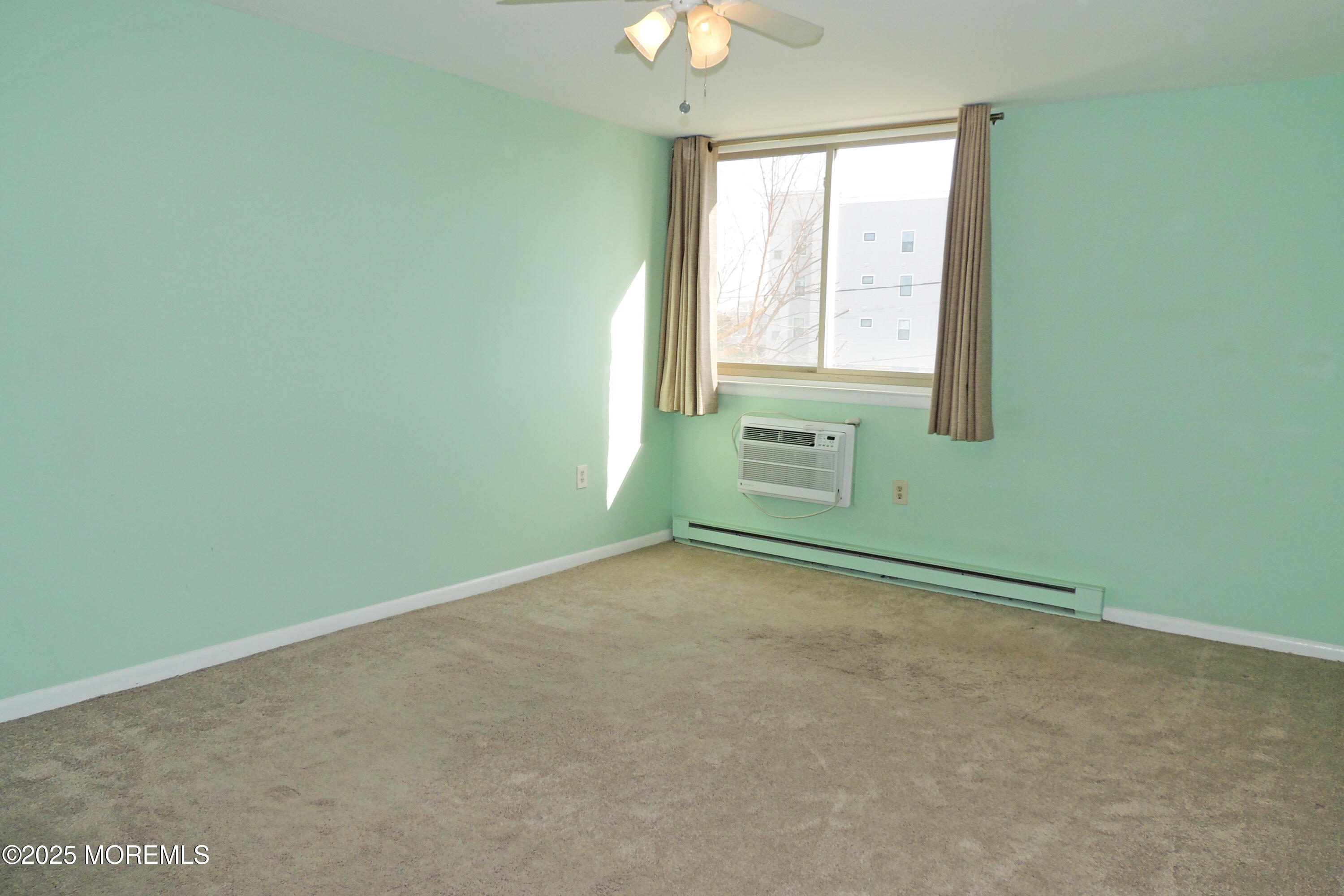 an empty room with chandelier fan and windows