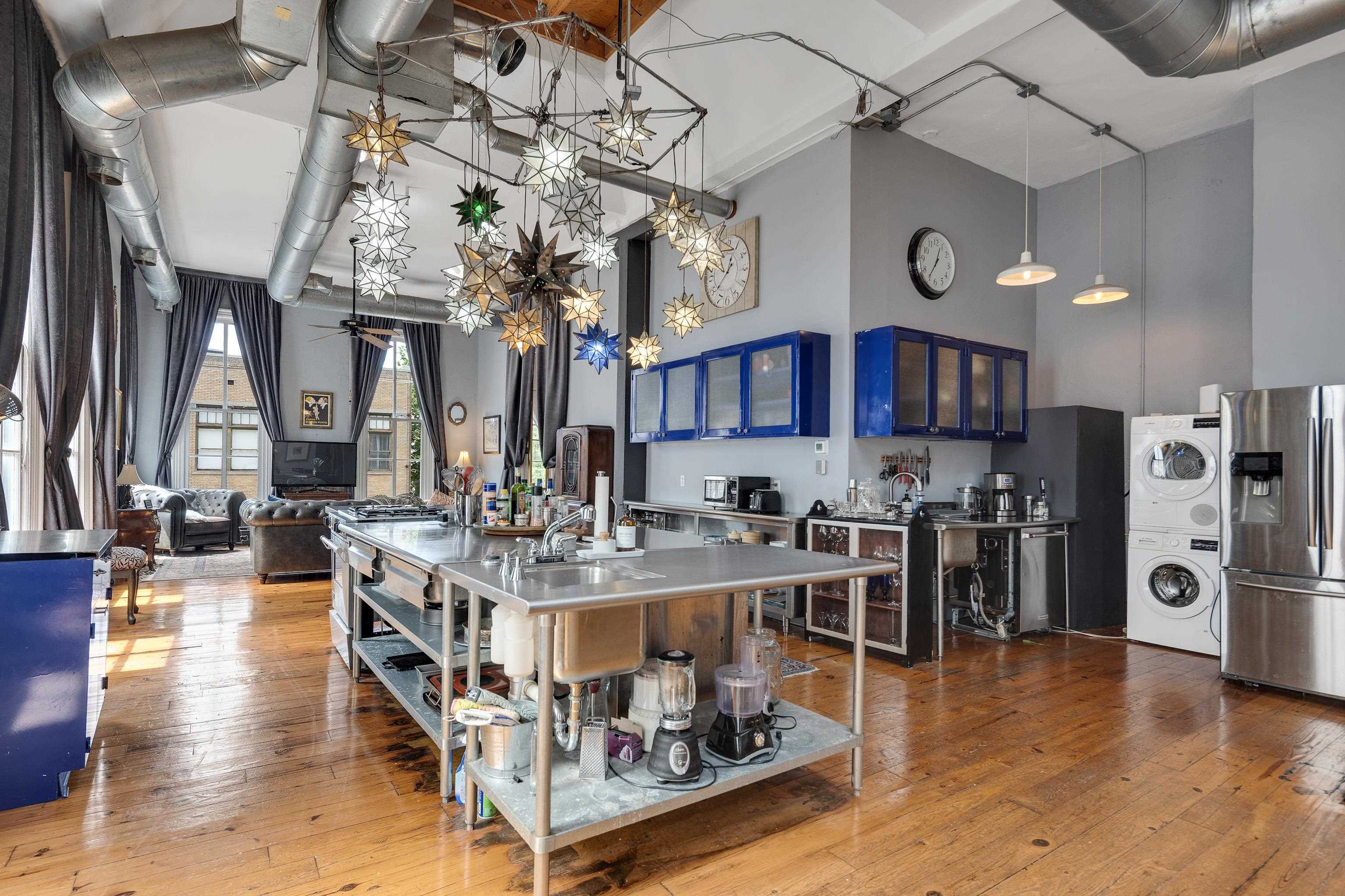 116 South Front Street, Unit 201 Memphis, TN 38103 - Photo 6 of 26 Kitchen with stainless steel counters, glass fronted cabinets, stainless steel refrigerator with ice dispenser, a high ceiling, and light wood-type flooring