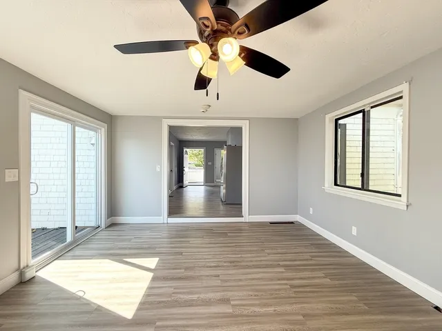 a view of an empty room with window and wooden floor