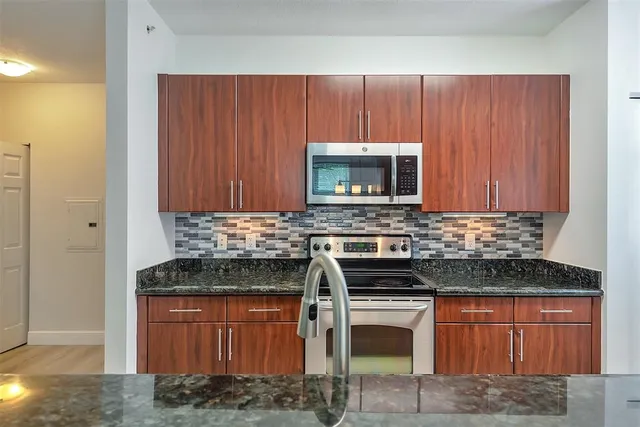 a view of kitchen with granite countertop cabinets and refrigerator