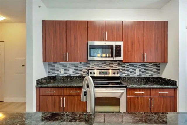 a kitchen with granite countertop a sink stove and microwave