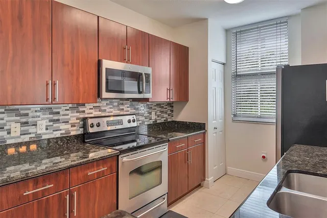 a kitchen that has a sink wooden cabinets and a stove top oven
