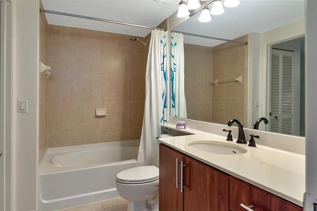 a bathroom with a granite countertop bathtub shower sink vanity and a toilet