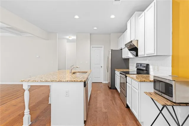 a kitchen with stainless steel appliances granite countertop a lot of counter space and wooden floors