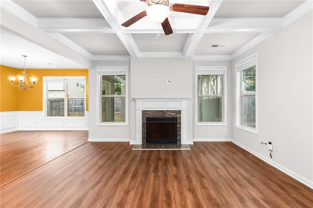 a view of an empty room with wooden floor fireplace and a window