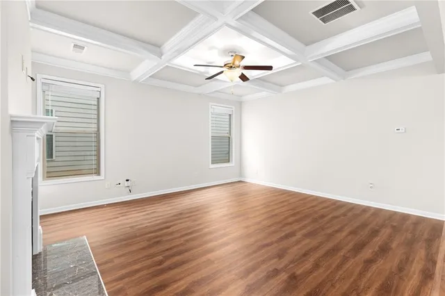 an empty room with wooden floor ceiling fan and windows