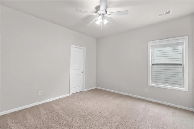an empty room with a chandelier fan and windows