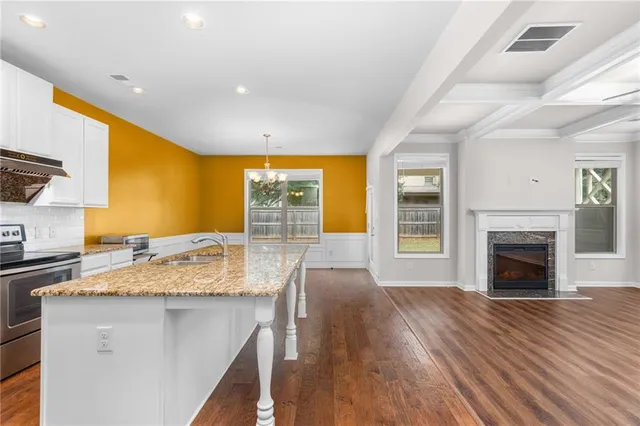 a view of kitchen with granite countertop cabinets stove and sink