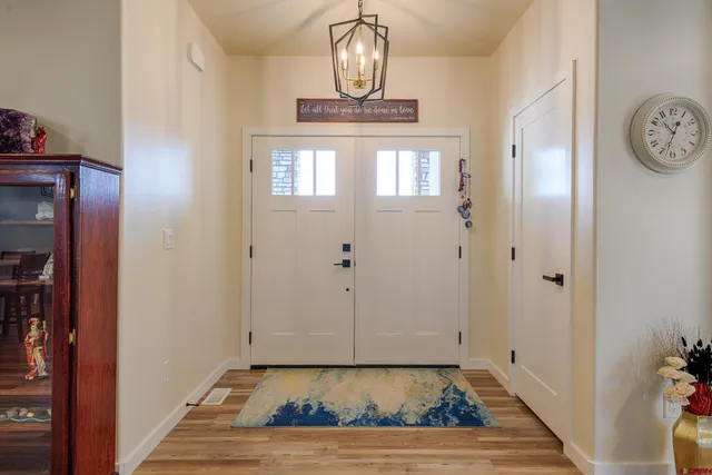 a view of a hallway with entryway wooden floor and a chandelier