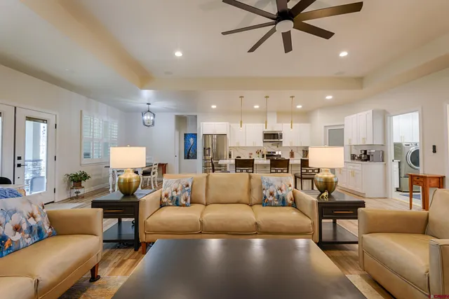 a living room with furniture kitchen view and a chandelier
