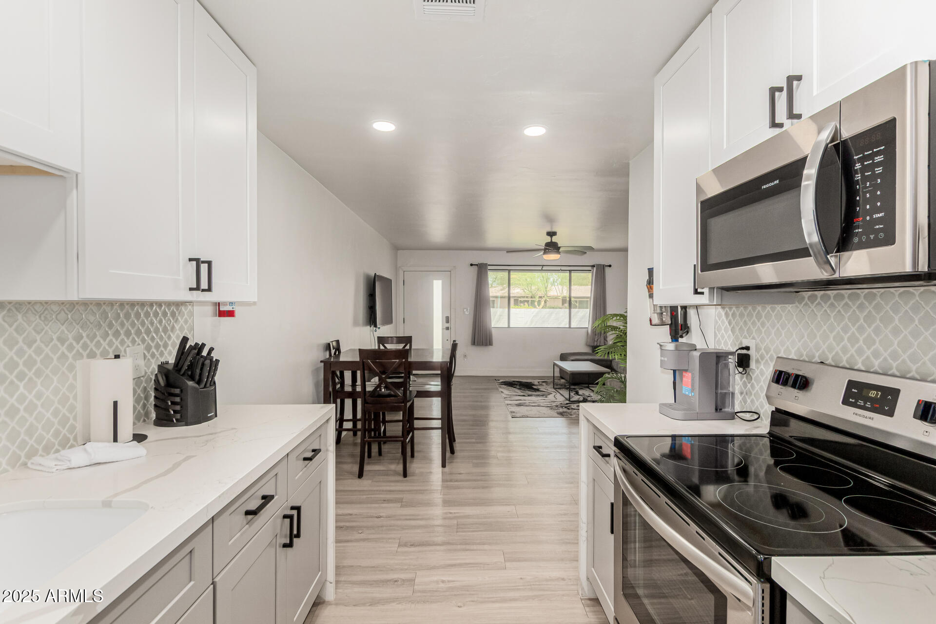 6628 East Avalon Drive, Unit 1 Scottsdale, AZ 85251 - Photo 11 of 29 a kitchen with stainless steel appliances kitchen island granite countertop a stove top oven a sink a dining table and chairs with white cabinets