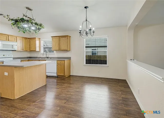 a view of a kitchen with kitchen island a sink wooden floor and a chandelier