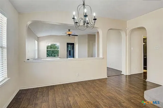 a view of a hallway with wooden floor and a chandelier
