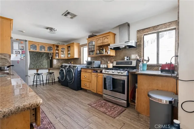 a kitchen with stainless steel appliances granite countertop a stove top oven a sink dishwasher a dining table and chairs with wooden floor