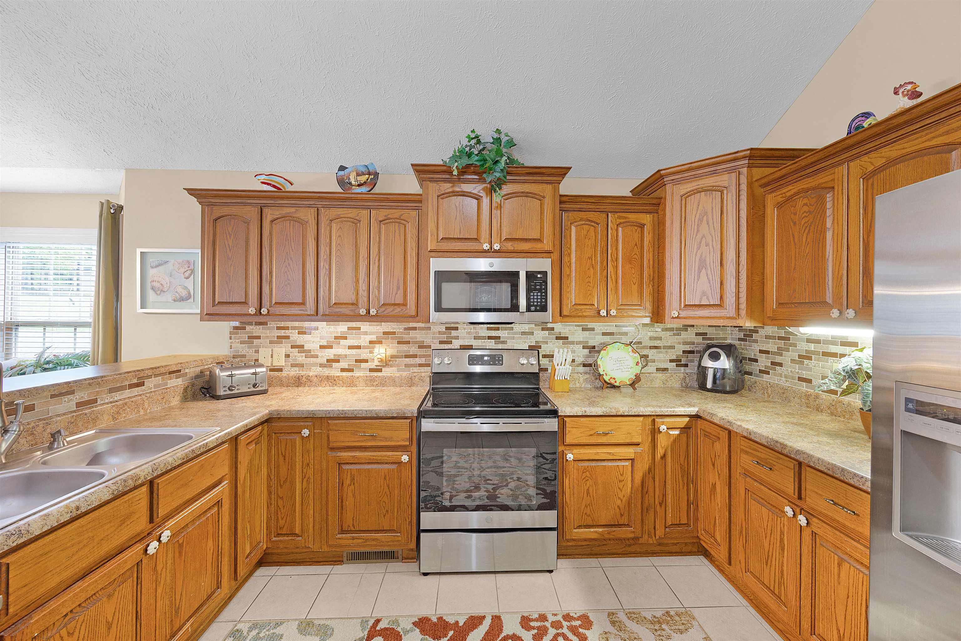 165 Ping Hl Cove Counce, TN 38326 - Photo 10 of 19 Kitchen with a textured ceiling, a sink, backsplash, light tile patterned floors, and stainless steel appliances