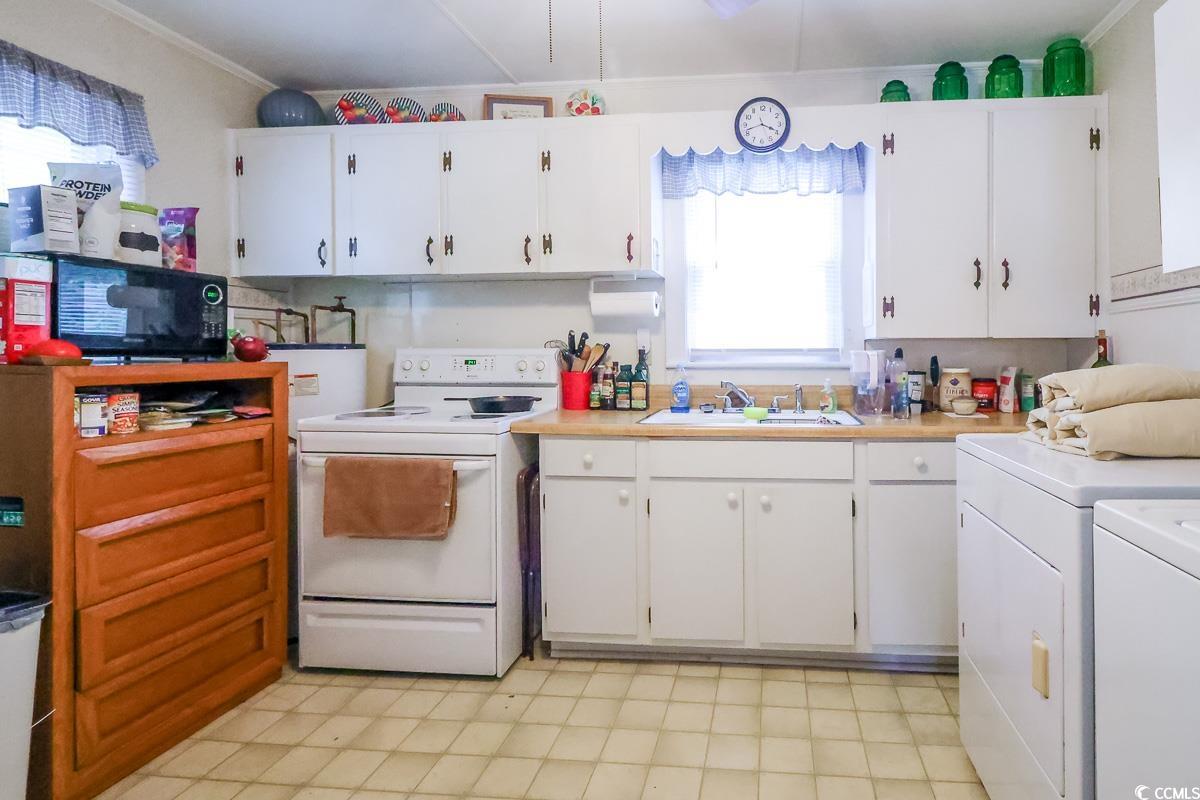 404 13th Avenue South Myrtle Beach, SC 29577 - Photo 30 of 38 Kitchen with white electric range, washer and clothes dryer, light floors, light countertops, and white cabinetry