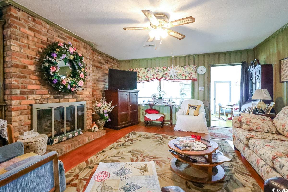 404 13th Avenue South Myrtle Beach, SC 29577 - Photo 5 of 38 Living room featuring a brick fireplace, wood finished floors, a ceiling fan, and a textured ceiling