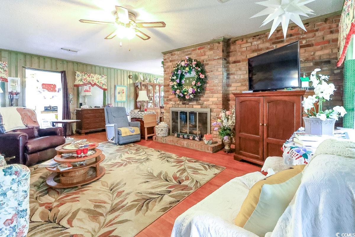 404 13th Avenue South Myrtle Beach, SC 29577 - Photo 6 of 38 Living area featuring a ceiling fan, a fireplace, wood finished floors, and a textured ceiling
