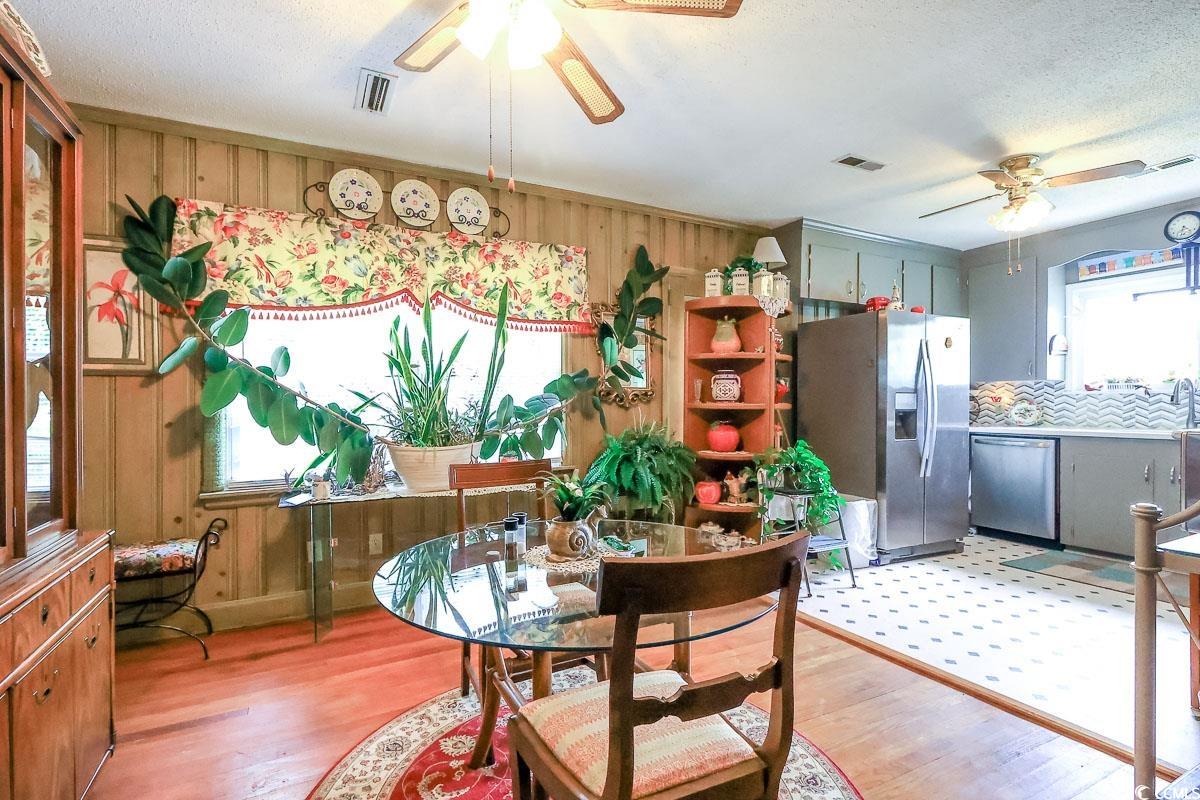 404 13th Avenue South Myrtle Beach, SC 29577 - Photo 9 of 38 Dining area with ceiling fan, light wood-style floors, wooden walls, and a textured ceiling