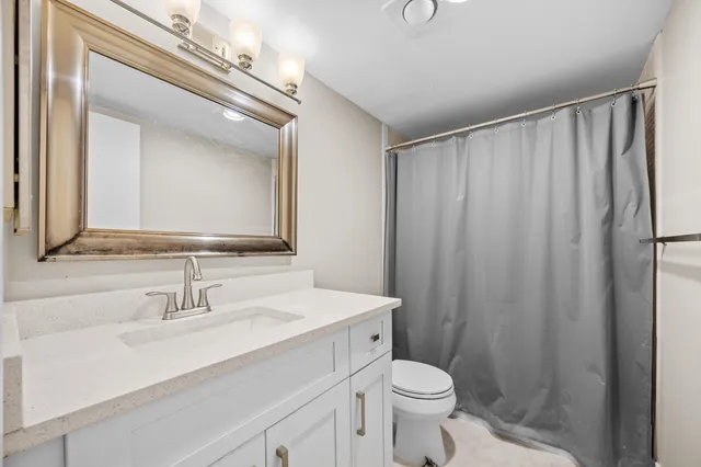 a bathroom with a sink a toilet a mirror and shower curtain