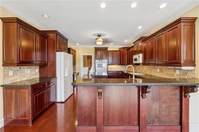 a kitchen with kitchen island granite countertop wooden cabinets a refrigerator and a sink
