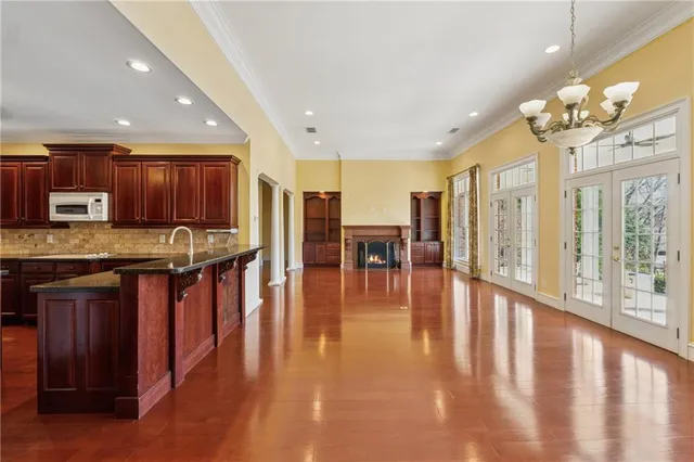 a kitchen with stainless steel appliances granite countertop a stove top oven a refrigerator a dining table and chairs with wooden floor