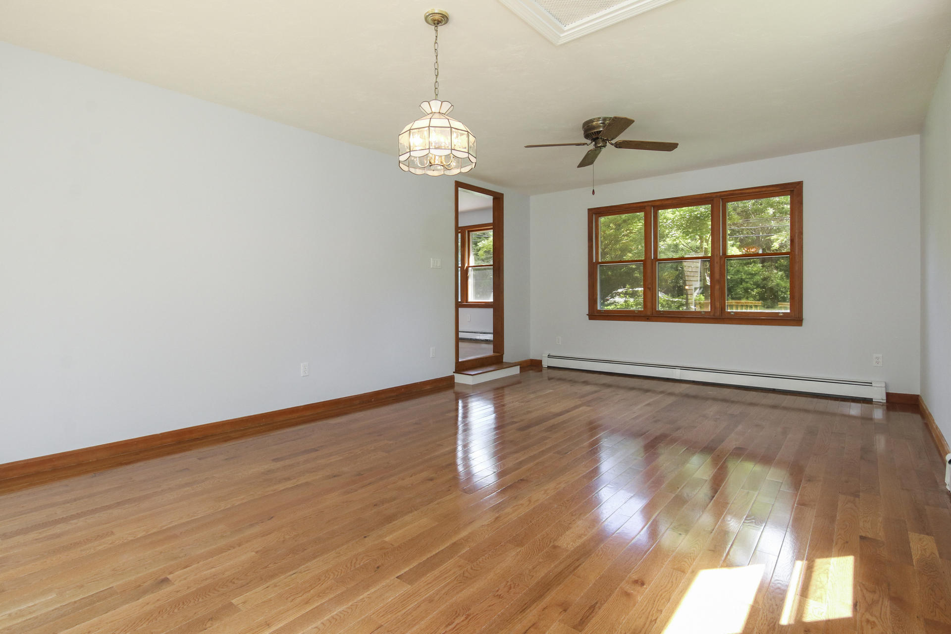 725 Old Stage Road Centerville, MA 02632 - Photo 14 of 53 an empty room with wooden floor chandelier and windows