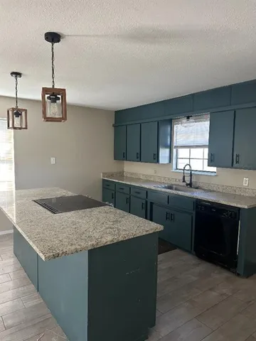 a kitchen with granite countertop a sink a stove and cabinets
