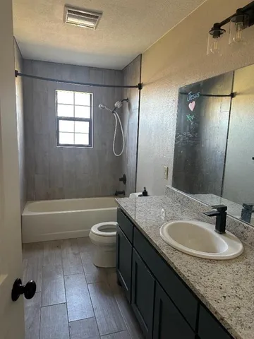 a bathroom with a granite countertop sink toilet and shower