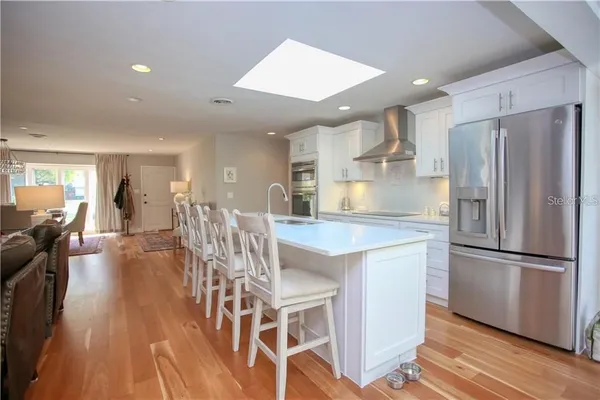 a kitchen with stainless steel appliances granite countertop a refrigerator a stove a sink dishwasher and a dining table with wooden floor