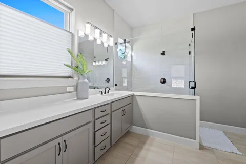 a bathroom with a double vanity sink a mirror and a bathtub