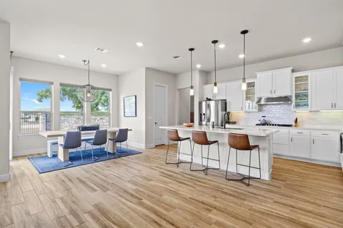a large kitchen with sink a refrigerator and wooden floor