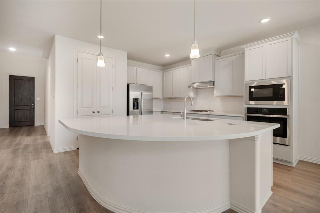 912 Alberta Spruce Road Justin, TX 76247 - Photo 13 of 35 a kitchen with kitchen island stainless steel appliances a sink a stove a microwave and cabinets