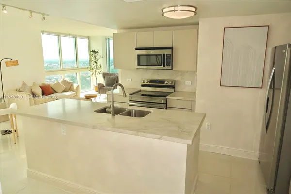 a kitchen with stainless steel appliances a refrigerator a stove a sink a stove a dining table and chairs