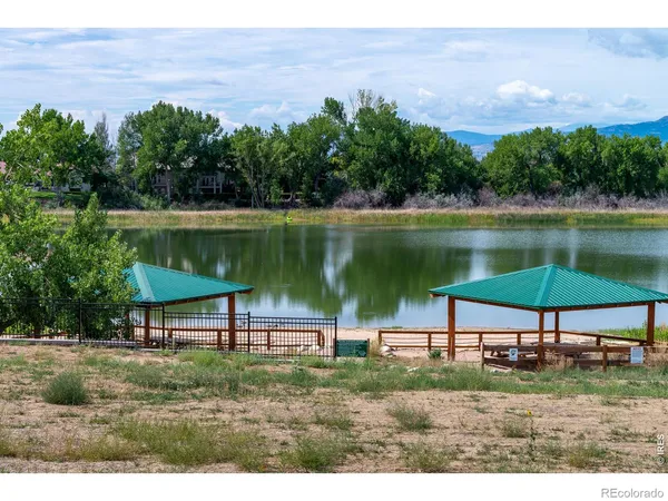 a view of a lake with a table and chairs under an umbrella