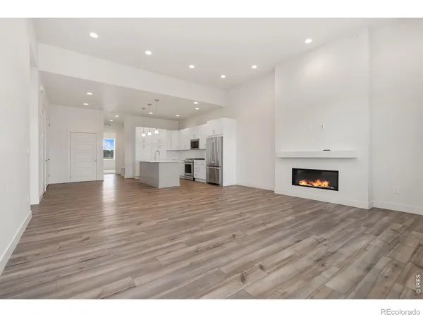 a view of an empty room and a kitchen