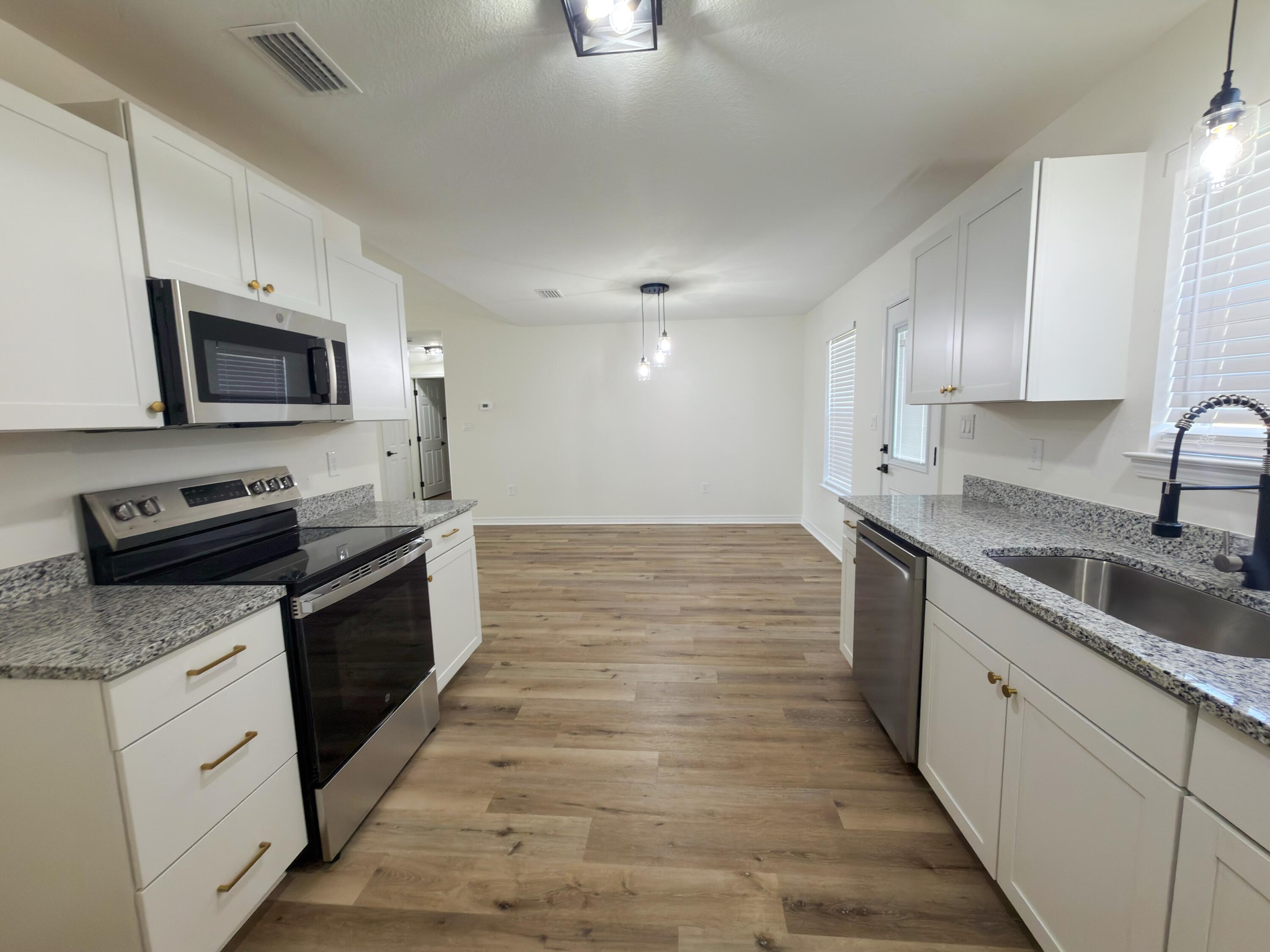 6121 Robin Road Crestview, FL 32539 - Photo 4 of 26 a kitchen with granite countertop a sink dishwasher stove and oven with wooden floor