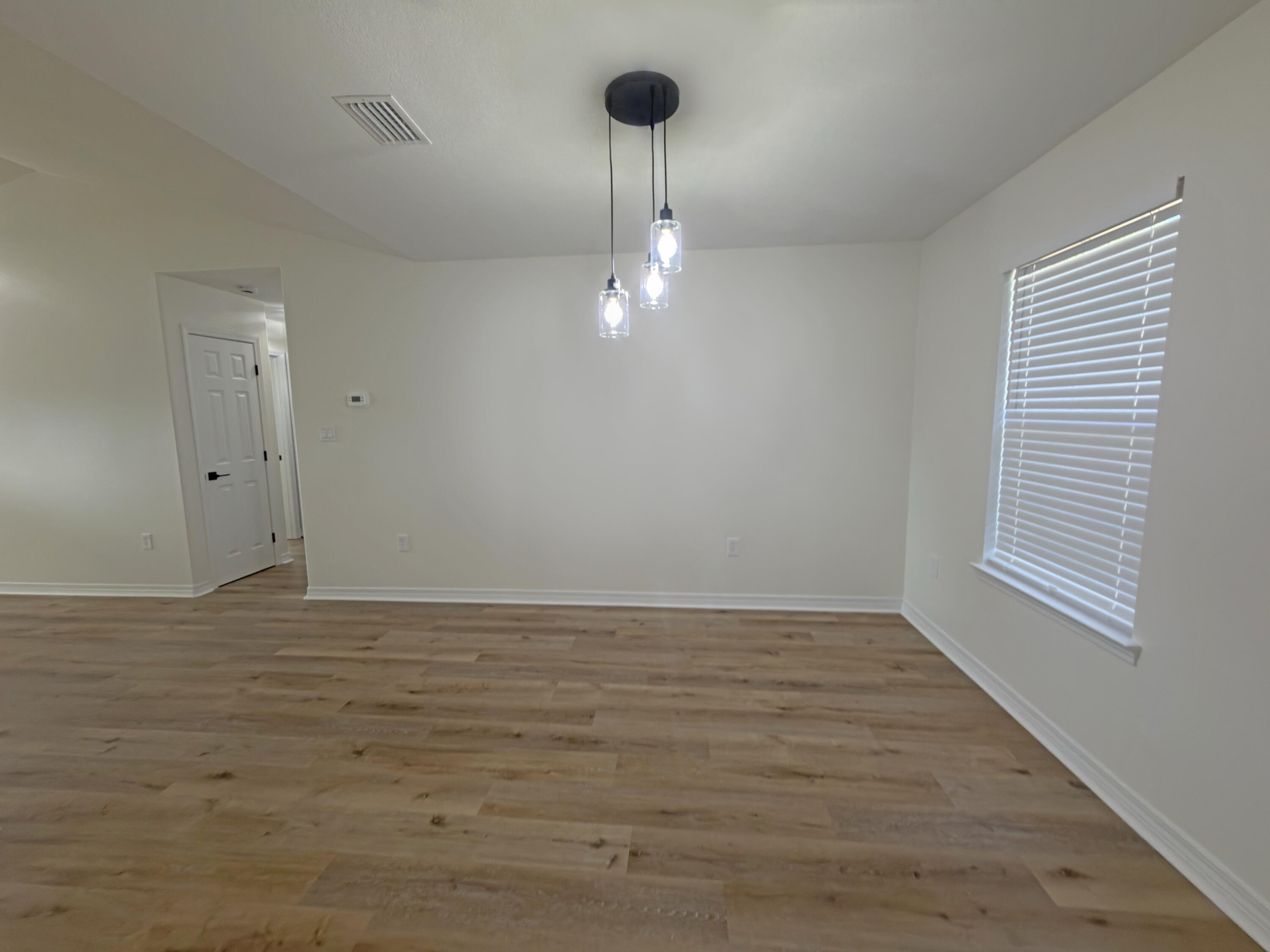 6121 Robin Road Crestview, FL 32539 - Photo 7 of 26 a view of an empty room with wooden floor and a window