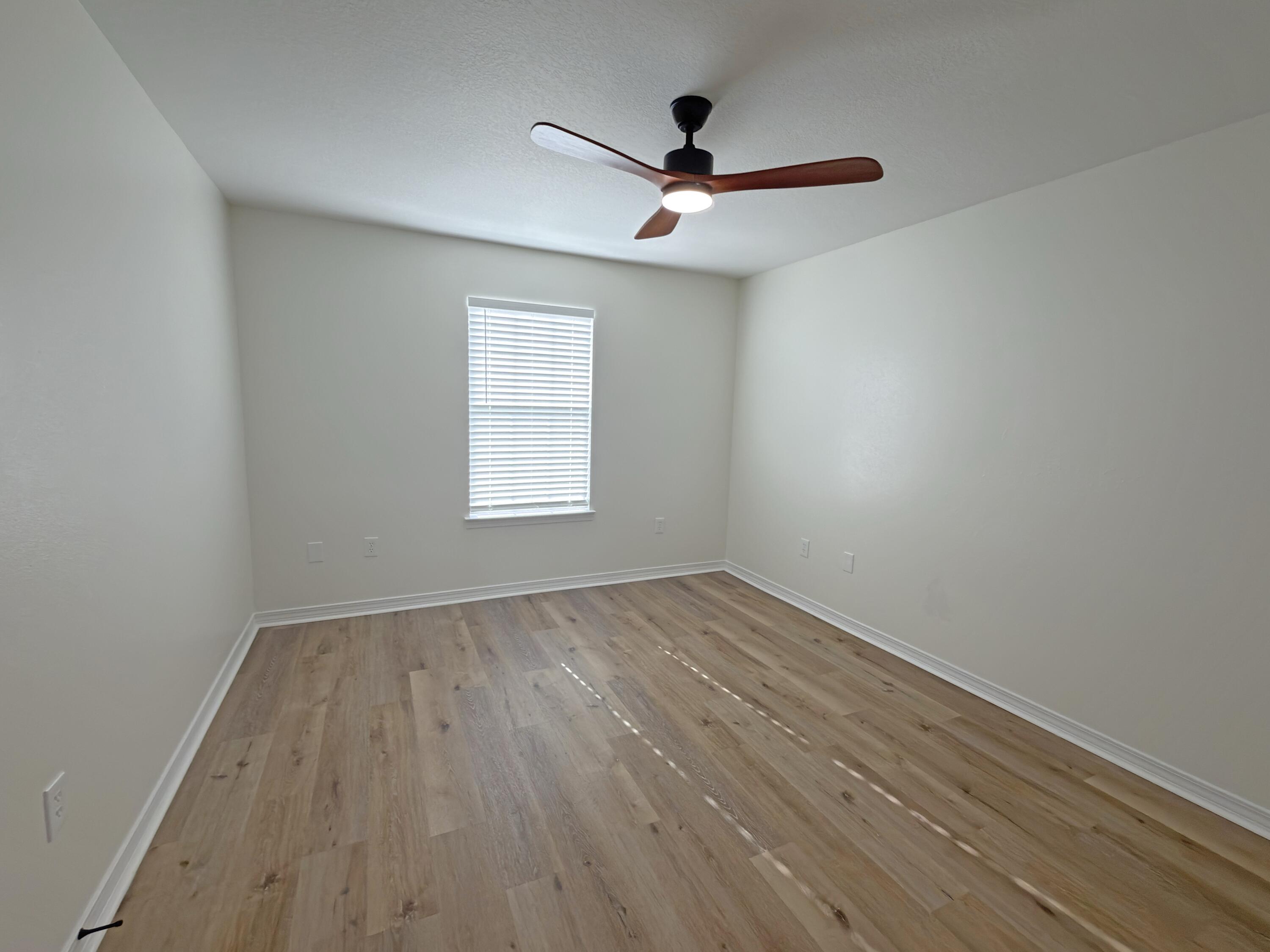 6121 Robin Road Crestview, FL 32539 - Photo 10 of 26 an empty room with wooden floor ceiling fan and windows
