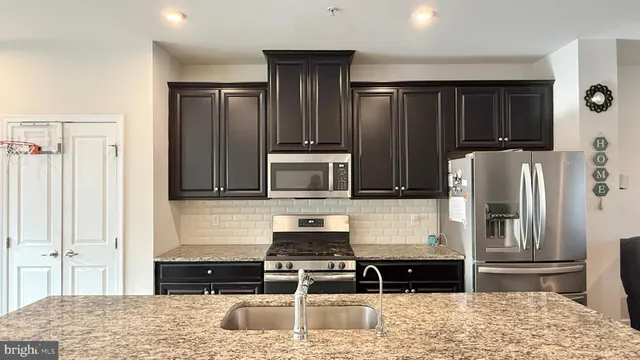a kitchen with granite countertop a refrigerator and a stove top oven