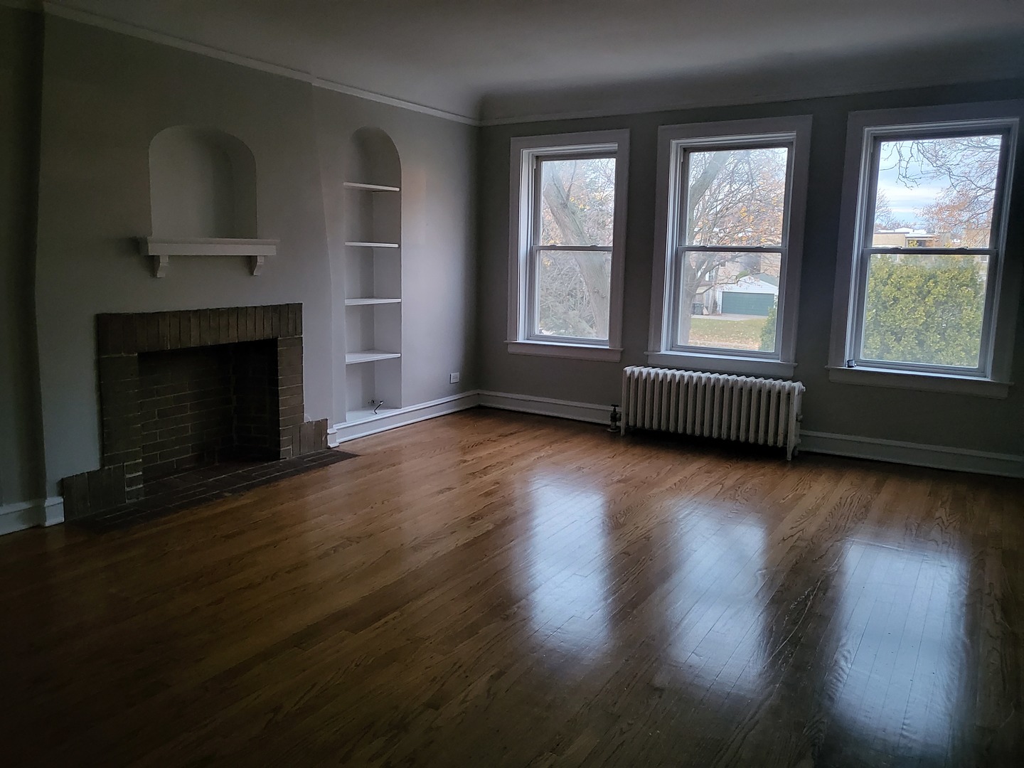 4831 Lee Street Skokie, IL 60077 - Photo 6 of 12 an empty room with wooden floor fireplace and windows