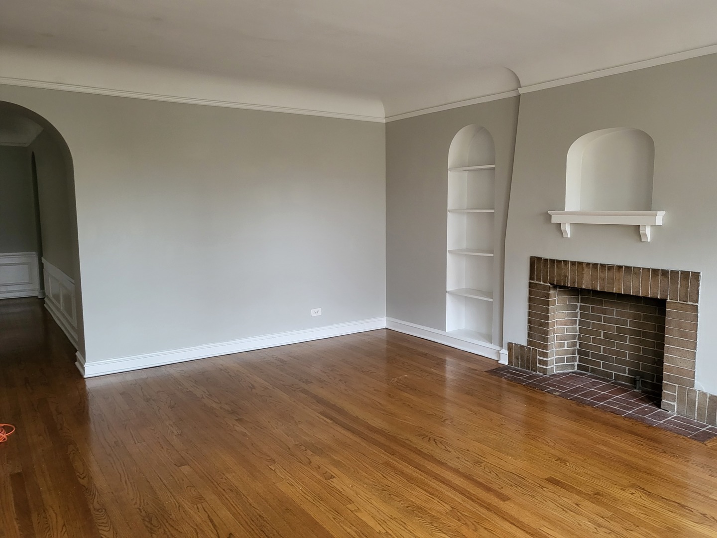 4831 Lee Street Skokie, IL 60077 - Photo 7 of 12 an empty room with wooden floor fireplace and windows