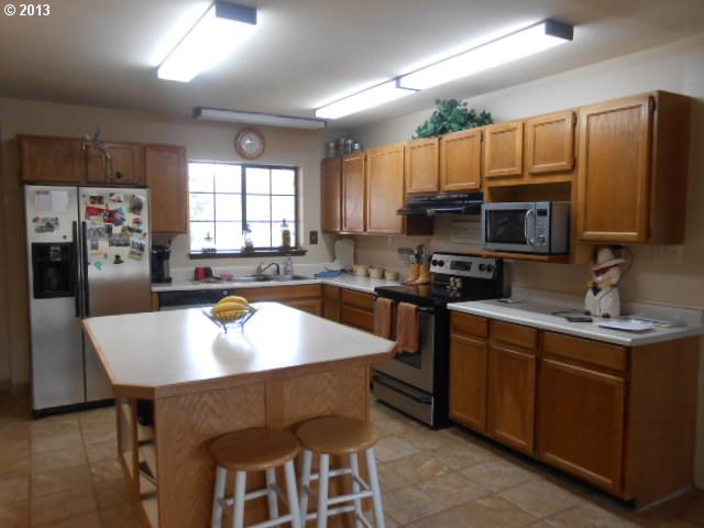 12015 South Fox Road Molalla, OR 97038 - Photo 4 of 16 a large kitchen with a table chairs refrigerator and a sink