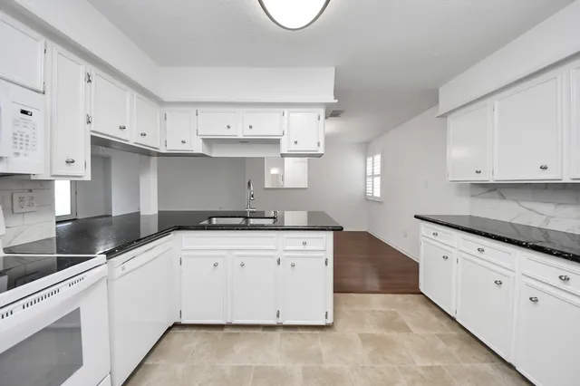 a kitchen with granite countertop a sink a stove and cabinets